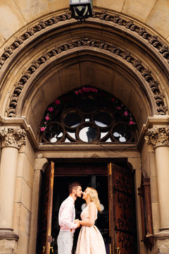 The boyfriend and his girlfriend stand face to face near entrance to a beautiful building