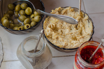 olives, hummus, pepper, hot sauce are on the table