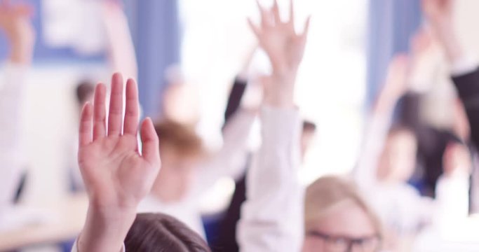 4k, School kids raising their hands to answer a question during a lesson. Slow motion.