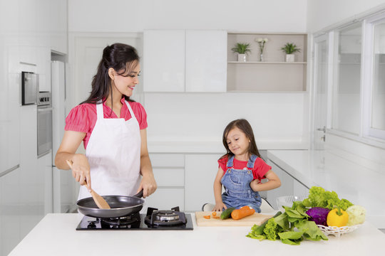 Mother with child preparing meals in the kitchen