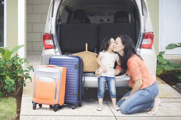Girl kissing her mother near the car