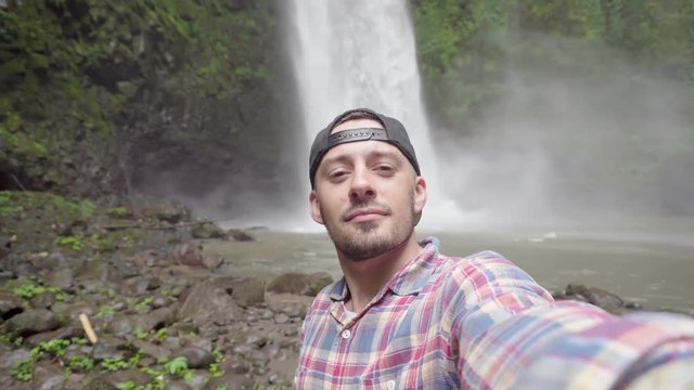 Selfie man. Male taking self photo near waterfall in park