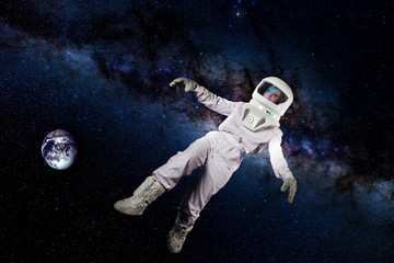 Fototapeta na wymiar Astronaut in space, in zero gravity on the background of the starry sky, galaxy, and planet earth. Elements of this image furnished by NASA.