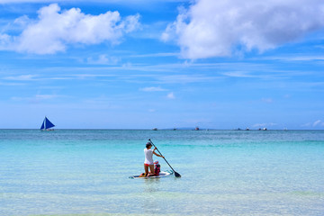 Woman is enjoying a view in standup paddleboarding over the ocean