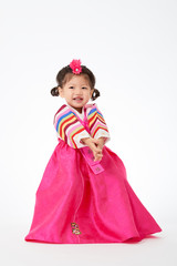 Smile Korean little girl wearing a Traditional Hanbok dress in white background. The characters on the dress means happiness and healthy.