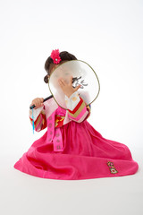 Smile Korean little girl wearing a Traditional Hanbok dress and holding a fan in white background. The characters on the dress means happiness and healthy. The character on the fan means happy.