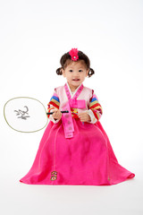 Smile Korean little girl wearing a Traditional Hanbok dress and holding a fan in white background. The characters on the dress means happiness and healthy. The character on the fan means happy.