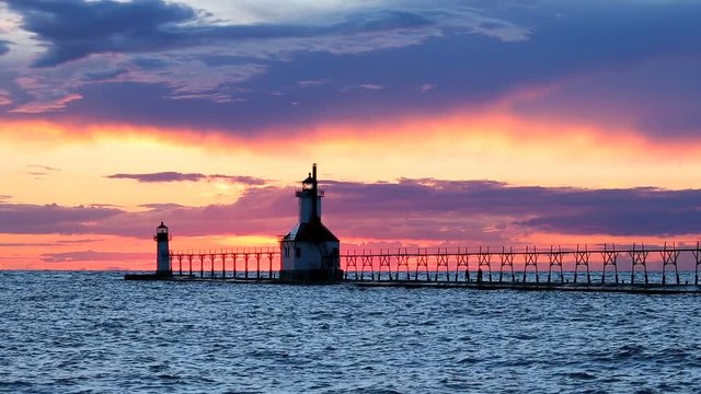 A dramatic sunset sky silhouettes the flashing lighthouses with elevated cat walks on Lake Michigan at St. Joseph, Michigan on the summer solstice.