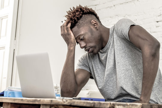 young desperate and overwhelmed black afro American student man in stress at home working stressed with laptop computer worried and tired