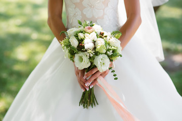 Hands of the bride and the bridal bouquet.