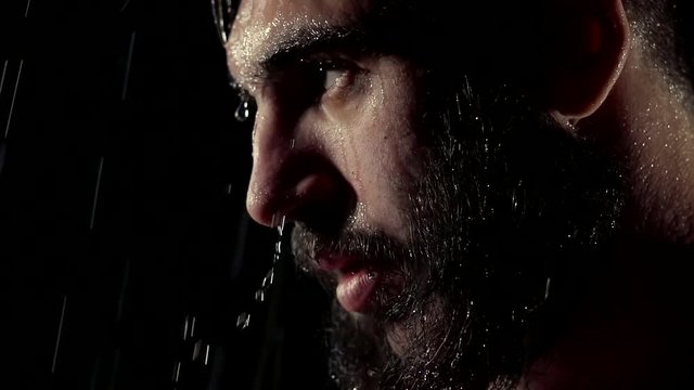 close up. portrait of brutal bearded men in the rain on his face as the flow drops