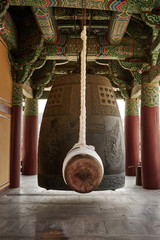 A large wooden ram hangs still beside an enormous iron bell at Bongeunsa Temple in Seoul, South...