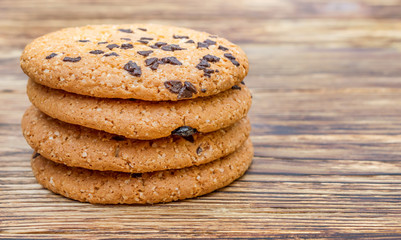 Stack of cookies with chocolate on wooden table.