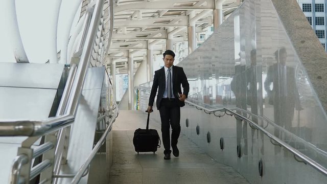 The young businessman walking dragging luggage to exit with hastiness