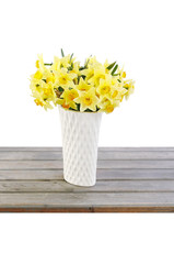 Bouquet of yellow daffodils in white ceramic vase.
