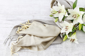 White lilies and green scarf on wooden background.