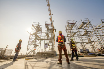 Construction engineers supervising progress of construction project stand on new concrete floor top...