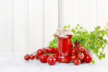Jar of tomato puree and fresh vegetables on wooden table