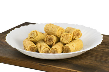 Crispy wafer rolls isolated on a white background. Rolled viennese waffles on white plate. Wafer rolls in a white plate.