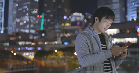 Young Man using smart phone in city at night