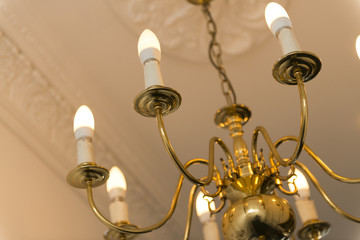 Brass Chandelier with Lit Bulbs with Ceiling in Background