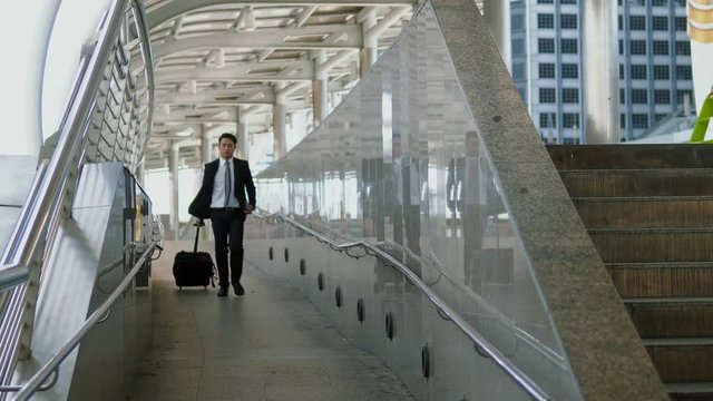 The young businessman walking dragging luggage with hastiness