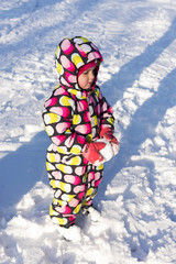 Child holding snow and playing on winter snowy day. On the nature.