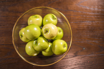 green apples in bowl on wooden table