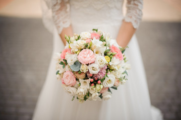 beautiful bride in a white dress holds bouquet outdoors