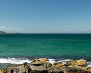Fototapeta na wymiar Rocks on the beach with horizon in the background - Manly Beach, Sydney, Australia