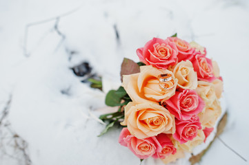 Wedding bouquet with rings at snow.