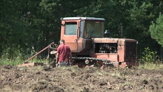 Old tractor plowing the soil. Farmer6