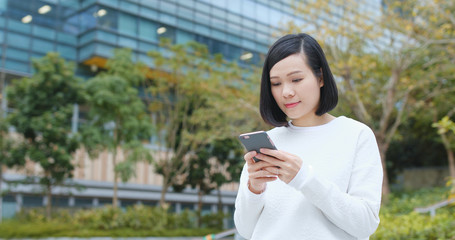 Fototapeta premium Woman look at mobile phone over business office background