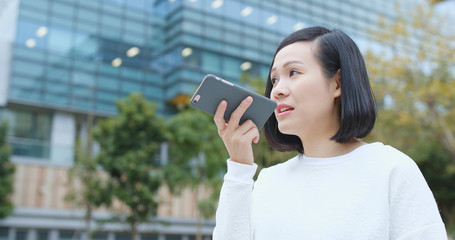 Woman sending audio message on cellphone at outdoor
