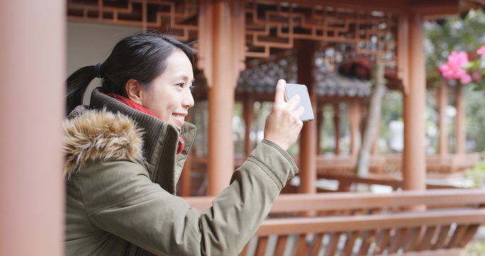Asian woman visit chinese garden and using cellphone to taking photo and video