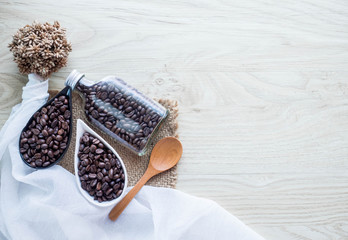 Black coffee seed in ceramic bowl and glass bottle with dry flower and wood spoon