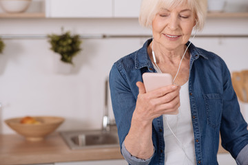 Pleasant smiling elderly woman using her smartphone