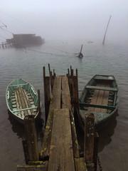 Two boats reside side by side to a pier in a gloomy morning in Marina di Ravenna, Italy.
