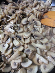 Sliced mushrooms are fried in a frying pan, mushrooms in a frying pan, mushrooms are prepared in the home kitchen, retro style, American cuisine, vegetarian food