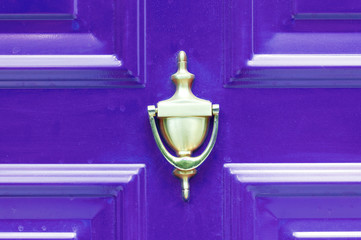 Old antique golden brass knocker on the abstract purple wooden doors for knocking close up