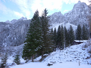 Beautiful winter landscape with mountains, forest, huts and park bench covered in fresh snow