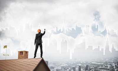 Man architect draw silhouette of modern city on blue sky. Mixed 