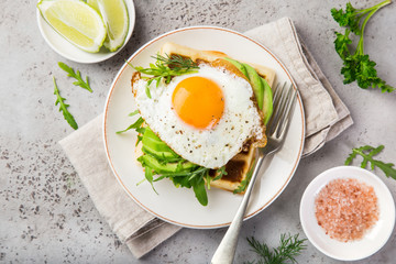 savory waffles with avocado, arugula and fried egg for breakfast