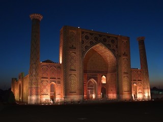 facade view with classic uzbek tiles and islamic mosaics of Ulughbek Madrassah, sunset in Registan...