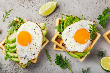 savory waffles with avocado, arugula and fried egg for breakfast