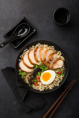 ramen noodle soup with chicken, shiitake mushroms and egg in black bowl