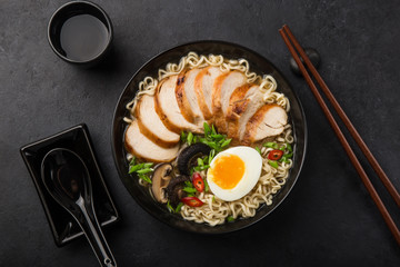 ramen noodle soup with chicken, shiitake mushroms and egg in black bowl