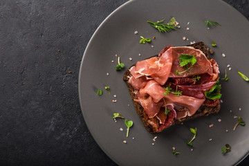 open sanwiches with dark rye bread, prosciutto and sun dried tomatoes