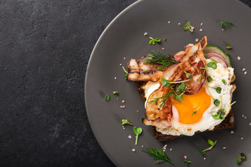 open sanwich with dark rye bread, fried egg and bacon,