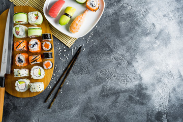 Sushi, rolls, rice with shrimp, sticks and knife on a dark background. Flat lay. Top view